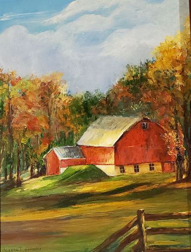A red barn surrounded by trees, a green field, and fence