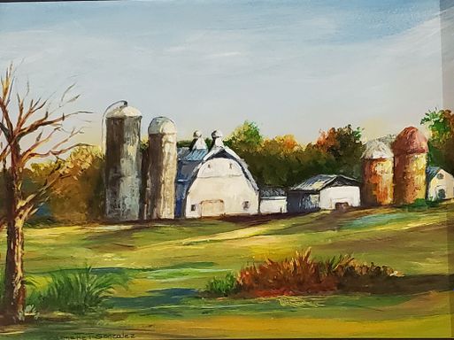 A white barn and silos in a grass field